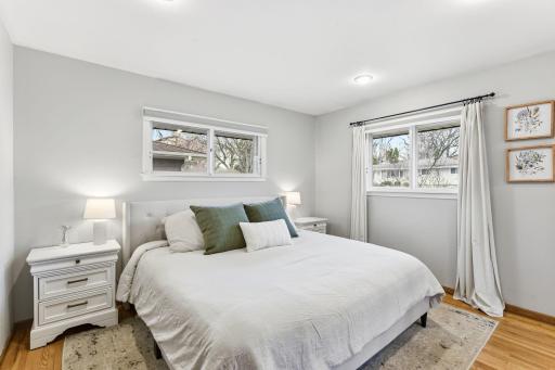 Primary bedroom with generous space, hardwood floors, and multiple windows bringing in natural light.