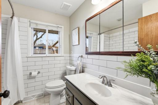Updated bathroom with a clean, modern feel, featuring a refreshed vanity, tile surround, and natural light from the window.