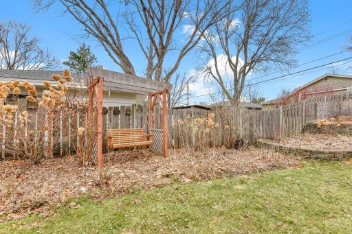 Charming backyard feature with pergola structure, adding character and potential for outdoor seating or garden space.