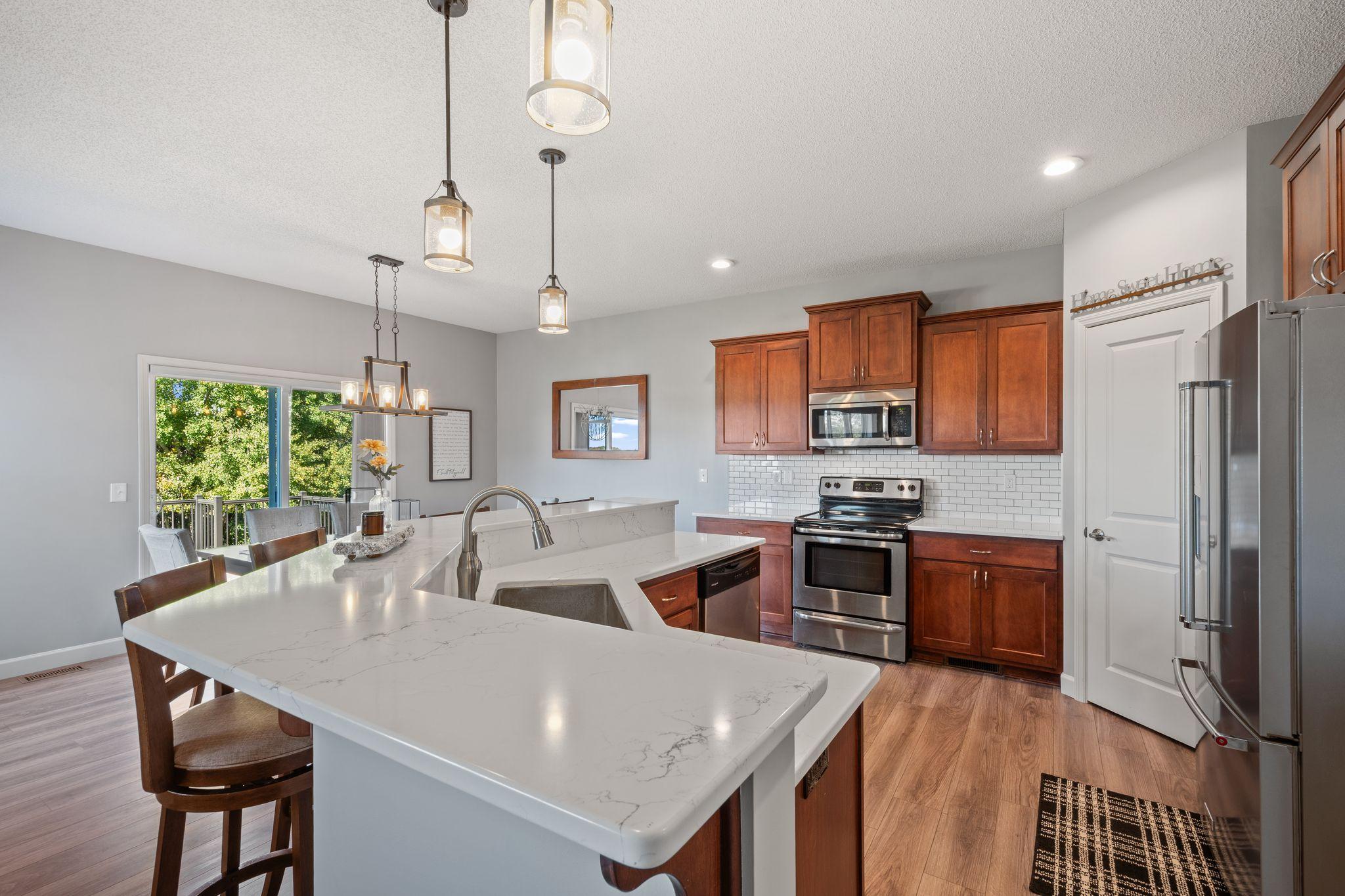 A perfectly appointed kitchen features quartz counters and stainless steel appliances.