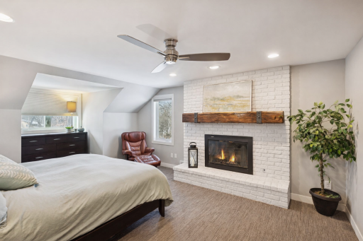 Primary suite with a wood burning fireplace. ***The fireplace bricks are currently red, but have been AI edited with white bricks