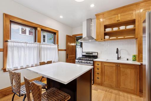 The kitchen features stainless steel appliances, gorgeous tilework, and a vented fan hoodâblending style & function.