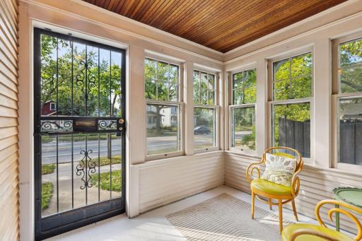 Adorable front porch has a bead board ceiling & is surrounded by windows.