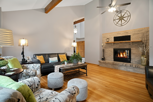 Large living room with soaring vaulted ceilings hardwood floors and double sided gas fireplace.