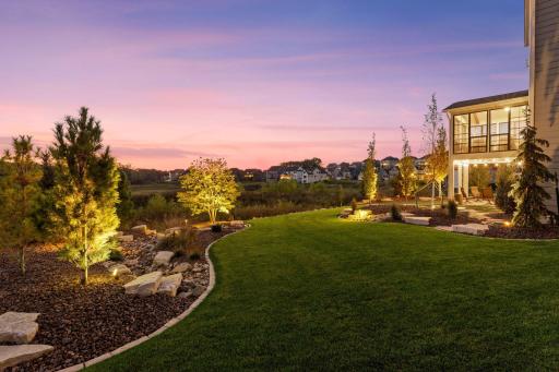 The beautifully landscaped yard comes alive at twilight, with soft landscape lighting highlighting lush greenery and creating a warm, inviting ambiance for evening enjoyment