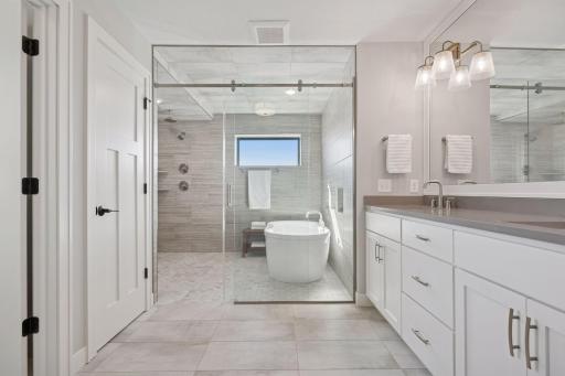 The private primary ensuite is a spa-like retreat, featuring a glass-enclosed wet room with a soaking tub, dual rain showers, and a dual-sink vanity designed for ultimate relaxation