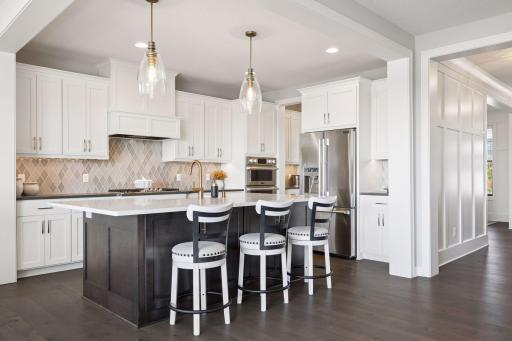 The kitchen shines with a quartz-topped island offering ample seating, complemented by a stylish, tasteful backsplash