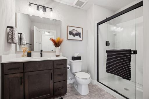 The lower-level Â¾ bath features a spacious walk-in shower, sleek tile flooring, and a large vanity