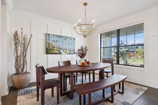 The formal dining room exudes sophistication with its elegant ceiling light and wood-paneled accent wall.