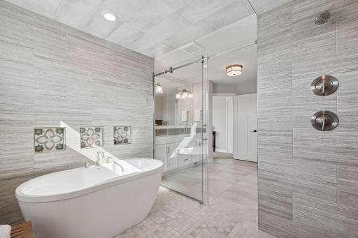 The wet room is a showpiece of design, featuring three custom-tiled bath niches and seamless tilework across the floor, walls, and ceiling for a truly luxurious finish