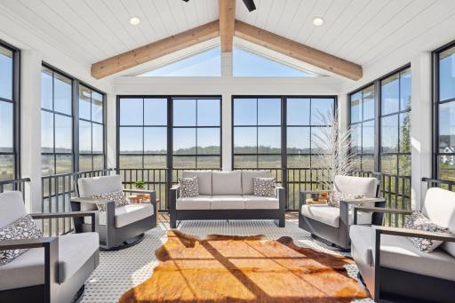 The three-season porch offers sweeping 180-degree views of wetlands and trees, framed by a vaulted ceiling and rustic wood beams