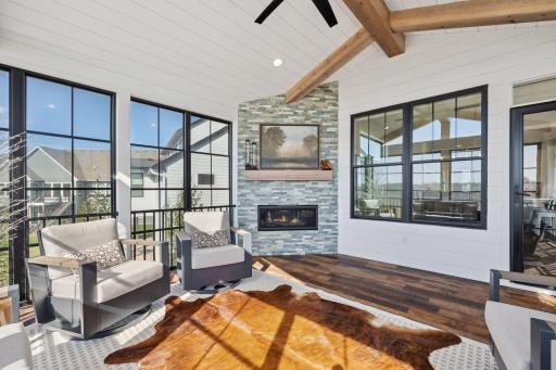 Cozy and refined, the three-season porch features a gas fireplace with floor-to-ceiling stone tile surround and a stylish ceiling fan overhead