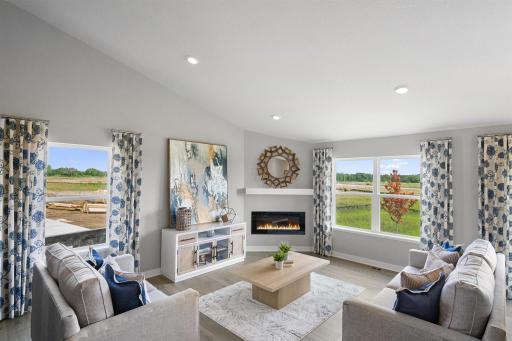 The living room is punctuated by an electric fireplace-which serves as a cozy bookend to the area and highlights a space that's flooded in natural light via soaring windows overlooking the back of the home!