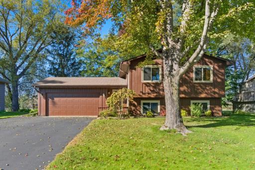 Beautifully maintained split-level home with mature trees, a lush front lawn, and an inviting front entry. The attached two-car garage and spacious driveway provide plenty of parking and curb appeal.