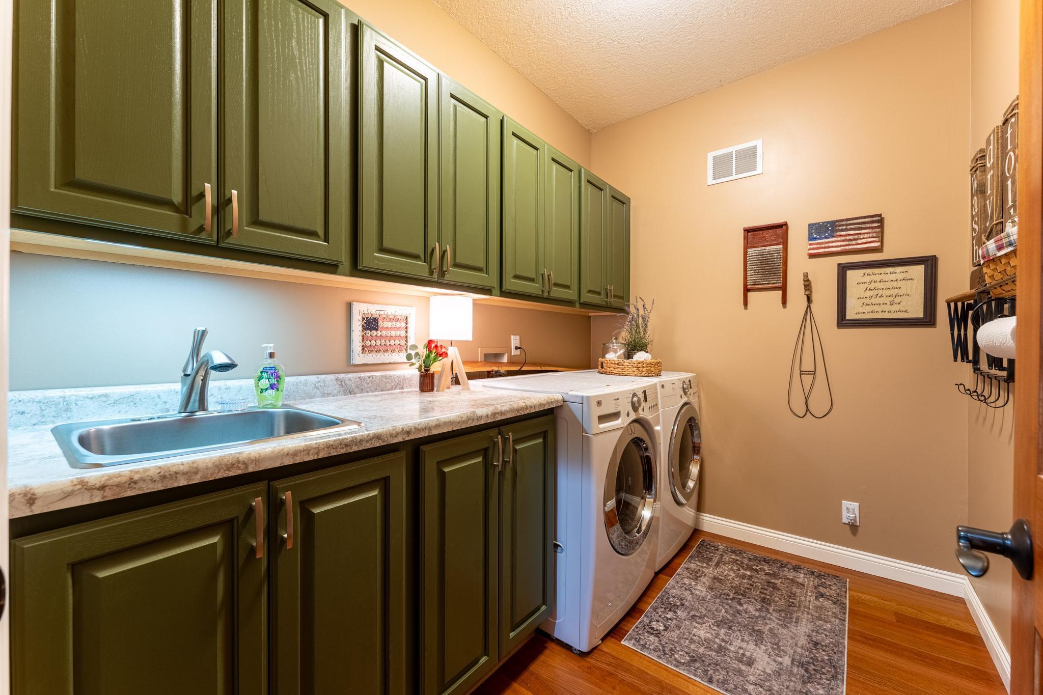 Main-level laundry with freshly painted cabinets (2026), utility sink & folding counter. Laundry room dimensions are 9 x 6.5 ft.