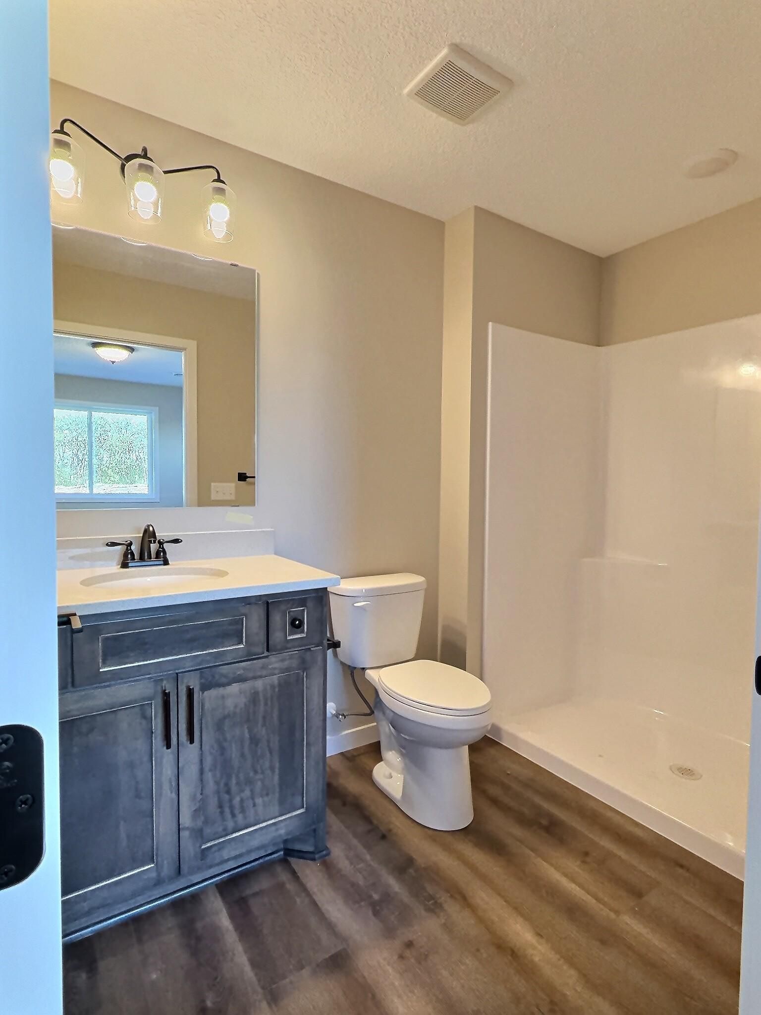 Here is the private bath and walk in shower. Vinyl plank flooring and quartz countertops.