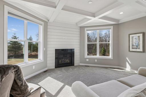 The sunroom off the kitchen boasts a coffered ceiling, gas fireplace and large windows overlooking the backyard.
