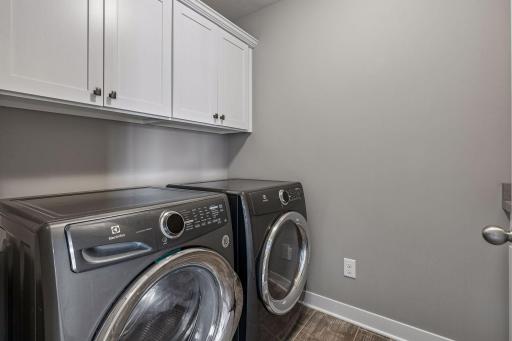 Upper-level laundry room with built in cabinetry for storage, a utility sink and Electrolux Washer and Dryer.