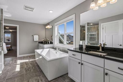 Large spa like primary bathroom features ceramic tiled flooring, two vanities with granite countertops, a soaking tub, separate toilet room and big walk-in shower.