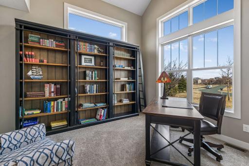 Main level office with a vaulted ceiling, glass French doors, and bookshelves (that will stay if buyers want them).