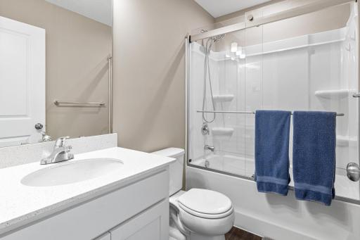 Full upper-level bathroom featuring a modern vanity with a quartz countertop and a tub/shower combination with a sleek glass sliding door. This clean, bright space perfectly serves the adjacent loft and guest bedroom for a complete guest wing.