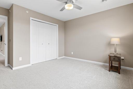 Another view of the upper-level bedroom, showcasing the functional layout with double closets for ample storage. This private guest suite features neutral tones, a ceiling fan, and soft natural light, perfect for visitors or a quiet hobby room.