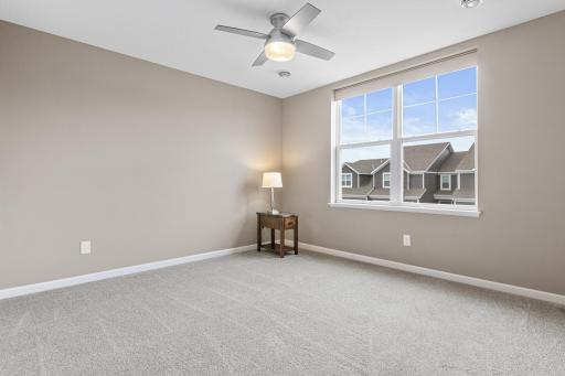Sun-filled upper-level bedroom featuring plush carpeting, a ceiling fan, and a large window offering expansive views. This private retreat includes double closets and easy access to the full guest bath, making it an ideal second suite.