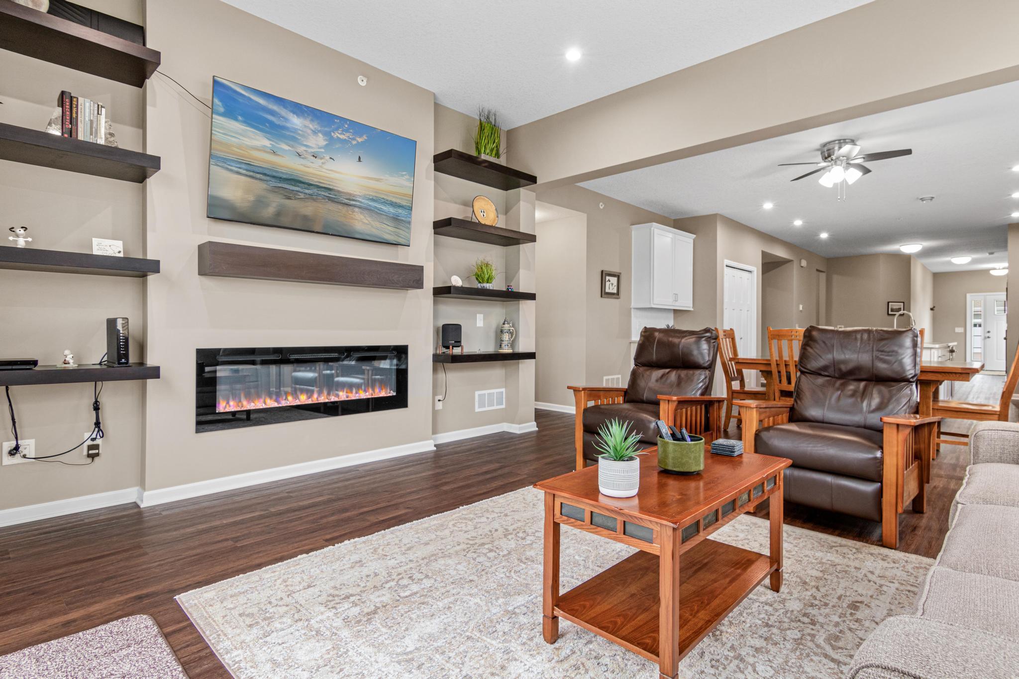 Open-concept living area featuring an electric fireplace with custom shelving, and a seamless flow to the kitchen and dining spaces.