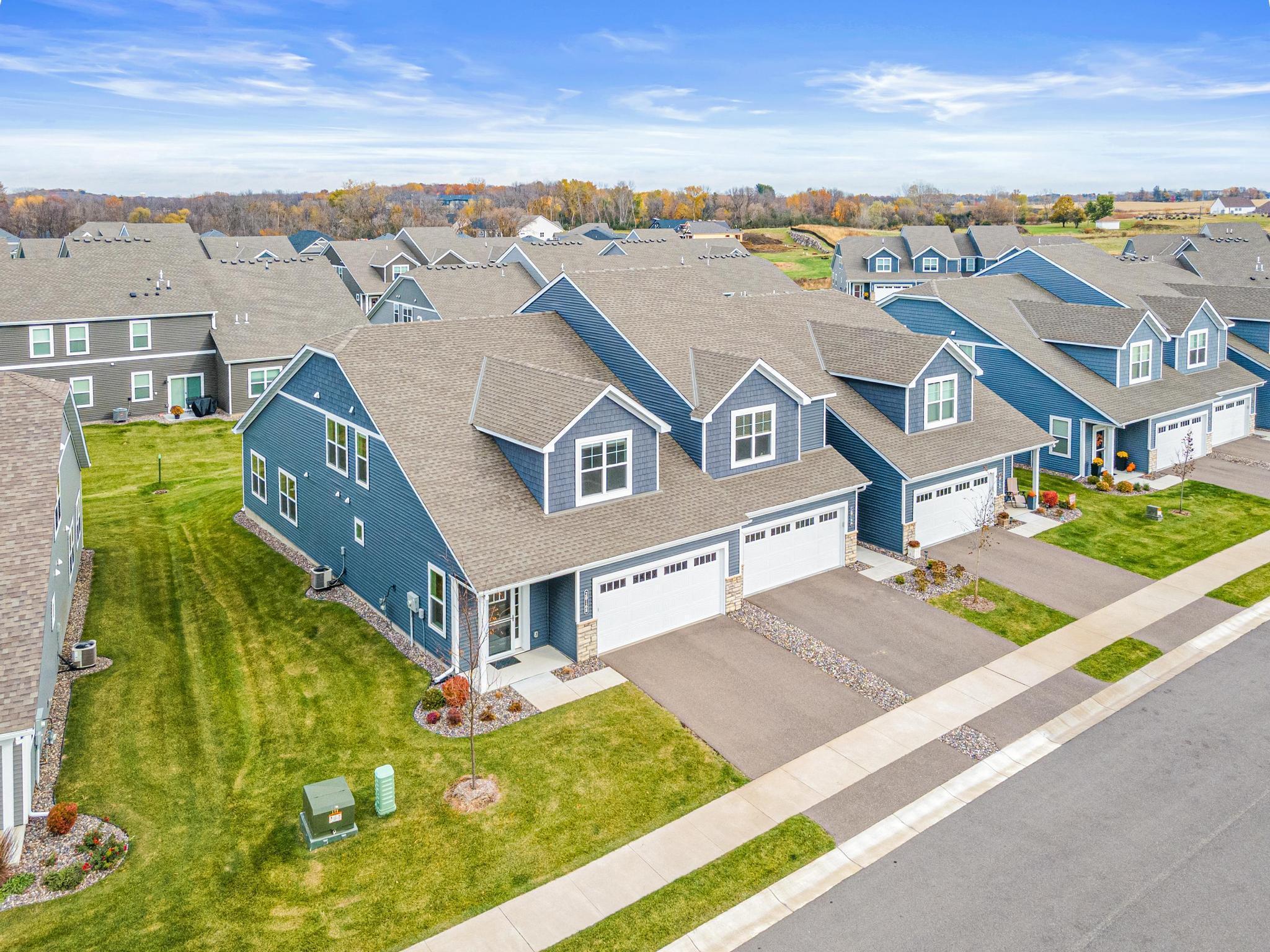 Aerial view of this premium end-unit townhome showcasing its prime location and expansive green space. Enjoy the privacy of an end unit in a quiet, modern community. Highlights the spacious side yard and professional landscaping.