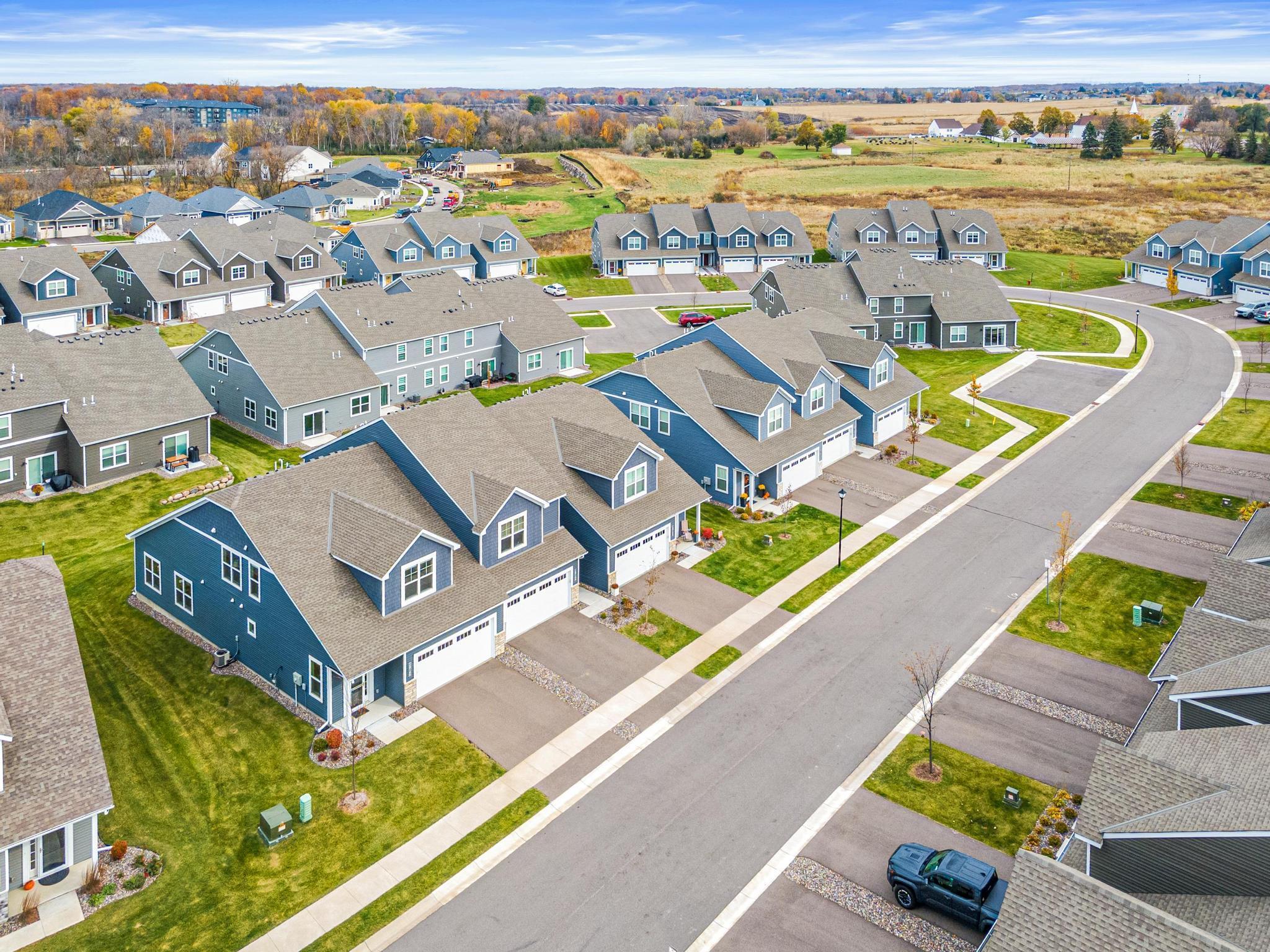 Photo from Fall 2025 showing the typical lush lawn and manicured landscaping. The premium end-unit location offers expansive green space and exceptional curb appeal, highlighting the meticulous care of this townhome community.