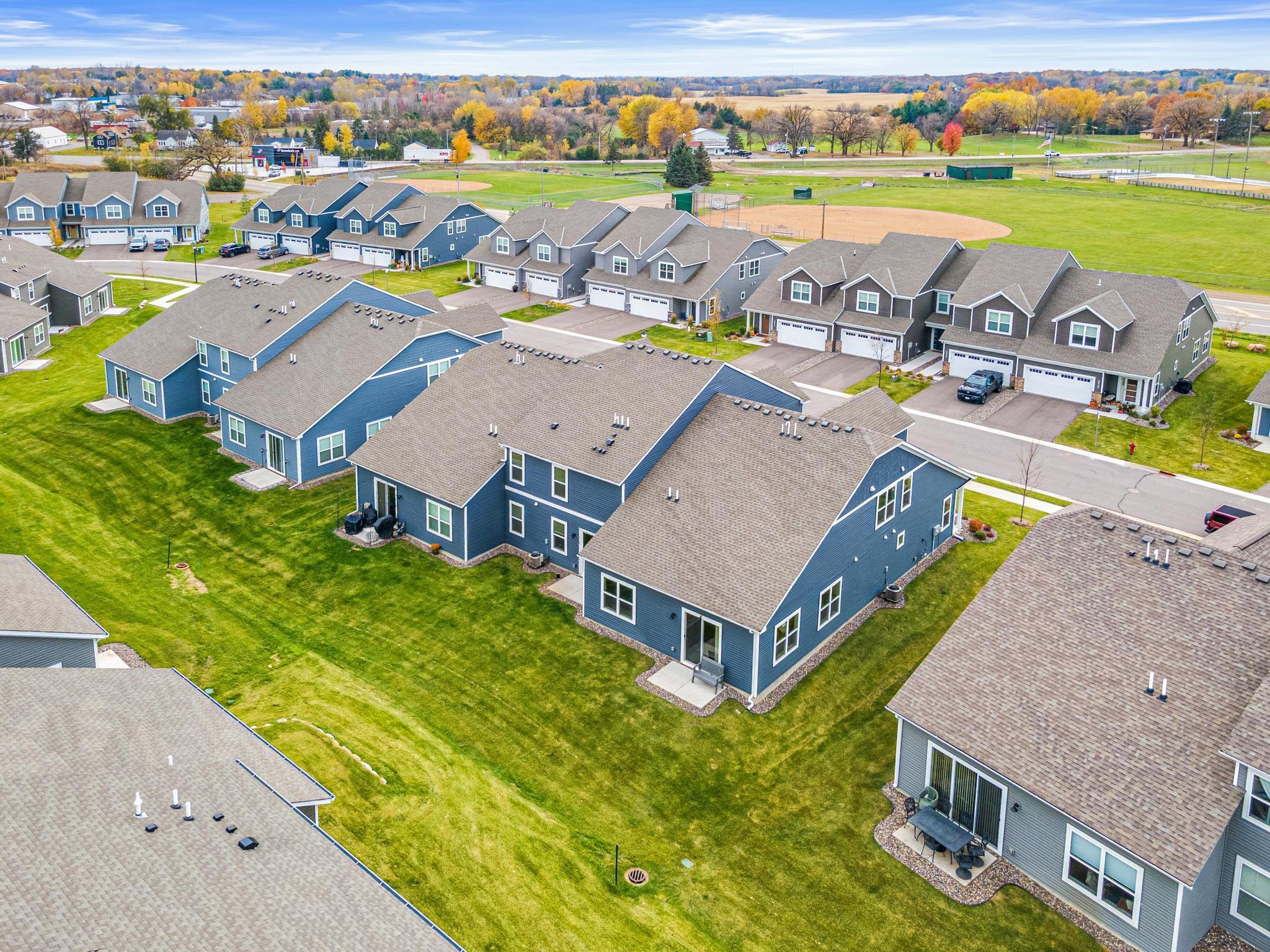 Photo from Fall 2025 showing the typical lush lawn and manicured landscaping. The premium end-unit location offers expansive green space and exceptional curb appeal, highlighting the meticulous care of this townhome community.