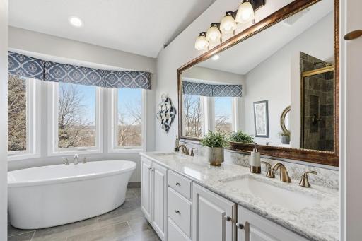 The remodeled primary bathroom offers elevated style in a new vanity, soaking tub and separate walk in tiled shower.