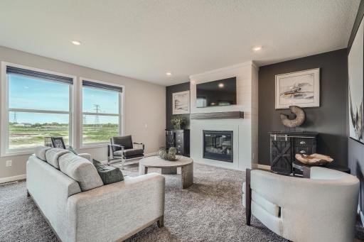 Photo is of the model. Spacious great room with an abundance of natural light and a fireplace.