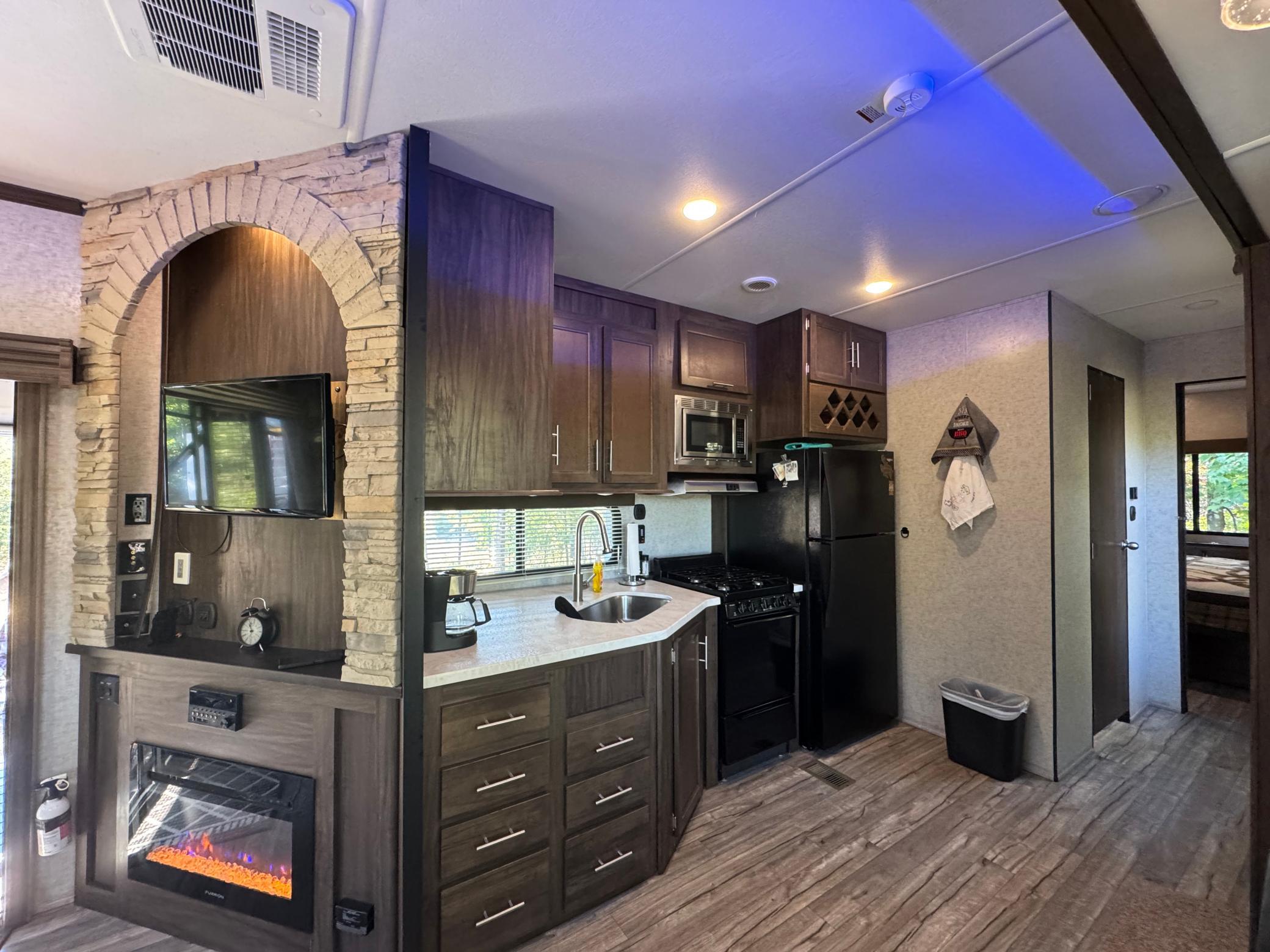 Can you believe this is a camper? Stone fireplace surround, electric heat fireplace, gorgeous kitchen with a full-size fridge and 4burner gas range.