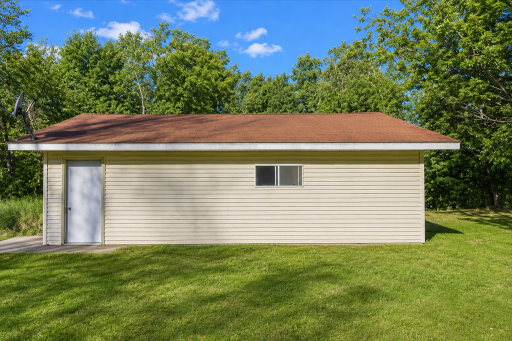 Detached garage side view highlights extra storage, mature trees, and the peaceful acreage setting near Dogfish Lake.