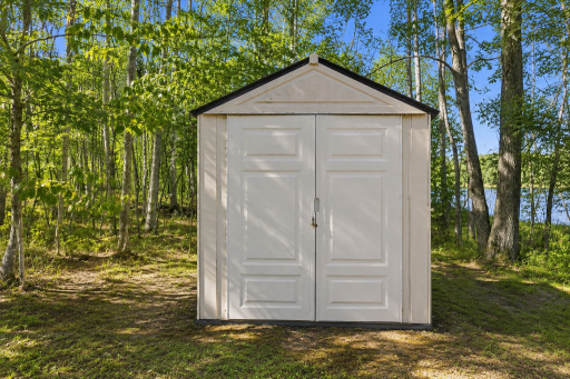 Storage shed near the wooded shoreline offers convenient space for tools, lake gear, outdoor equipment, and seasonal items.