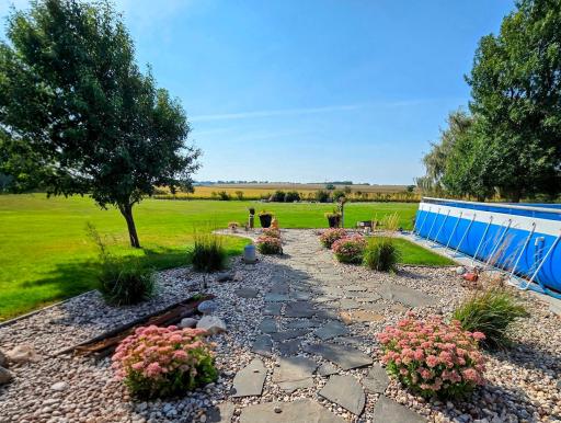 Backyard pathway accented with stone pavers & decorative landscaping bushes along side the pool.