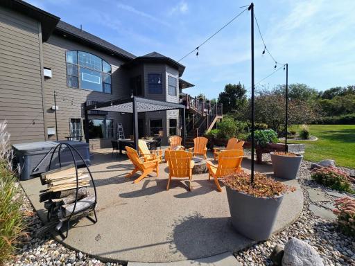 Round aggregate patio with firepit accented with planters in the summer time.