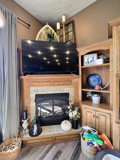 Corner oak fireplace is accented with stone makes the living room extra cozy.
