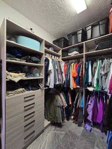 Walk in closet is well organized with plentiful drawers, storage compartments, room for generous amount of room for hanging clothes.