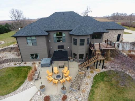 South view of the house. Round aggregate patio with firepit, walk out patio, composite steps to deck, and steps down to out door kitchen area.