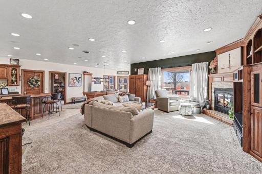 Spacious carpeted family room has recessed lighting, 6 panel doors, wet bar, rec area, door to walk out to patio, door to utility room, door to store room, & bedroom.