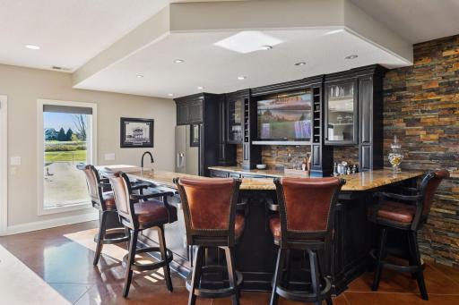Basement bar with stone wall behind it to add beautiful character. It has built ins for storage and glassware organization.