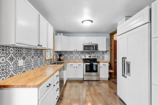 Butcher block countertops, custom white cabinets and gorgeous tile backsplash make this kitchen a dream!