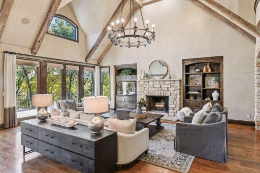 The great room captivates with its wood-beamed cathedral ceiling, limestone fireplace flanked by built-in cabinets, adjacent formal dining area with buffet, and expansive windows framing picturesque views of Silver Lake.