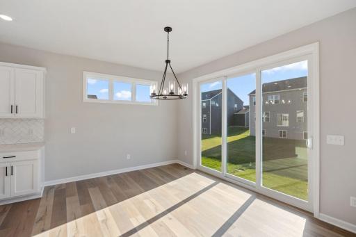 Informal dining room off the kitchen is filled with light from the oversized patio door and added transom windows.