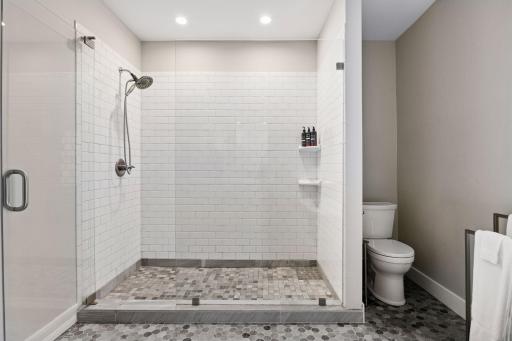 The separate tiled shower offers a frameless glass enclosure.