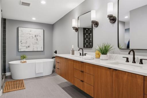The spa bathroom features a freestanding soaking tub and floating walnut vanities.