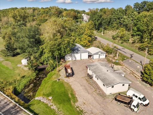 Aerial view showing the creek running through the property and the foot bridge. Vehicles and dumpster have been removed.