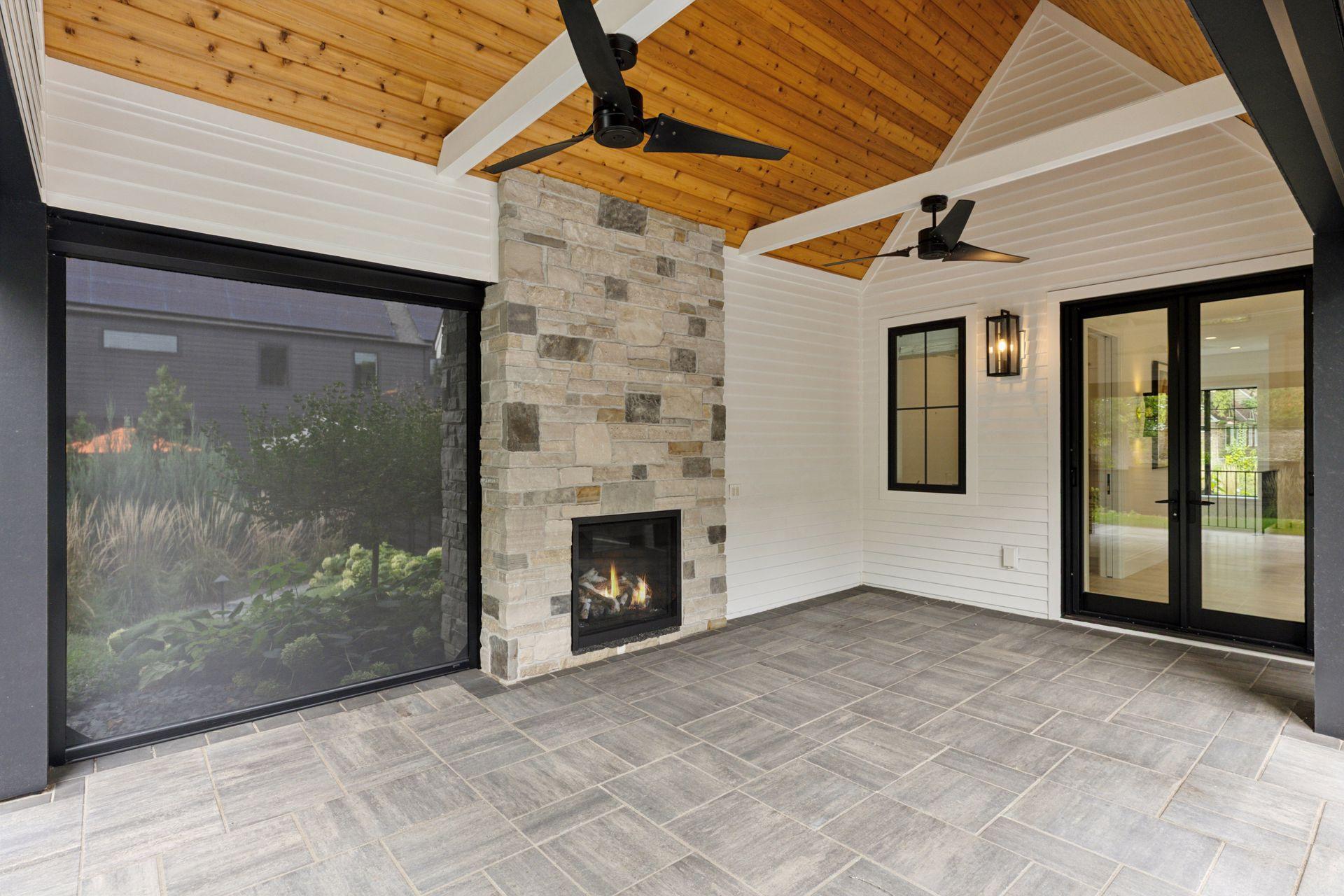 View inside the screen porch with phantom screens, fireplace, wood ceilings and tall vaults